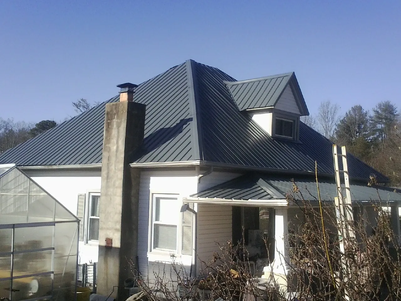 Dark blue standing seam metal roof on a white farmhouse with dormer — Slate & Tile Roof Repair by Roofing Brothers in Eden Prairie