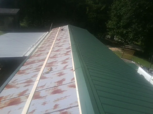 Old rusted panels beside newly installed green metal roofing — Wind Damage Roof Repair by Roofing Brothers in Eden Prairie