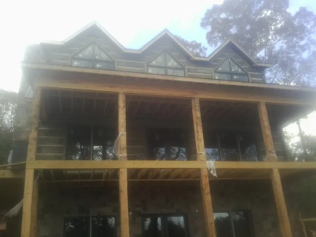 Dormers and porch framing on a large log home under construction — Roof Coating work by our crew in Eden Prairie