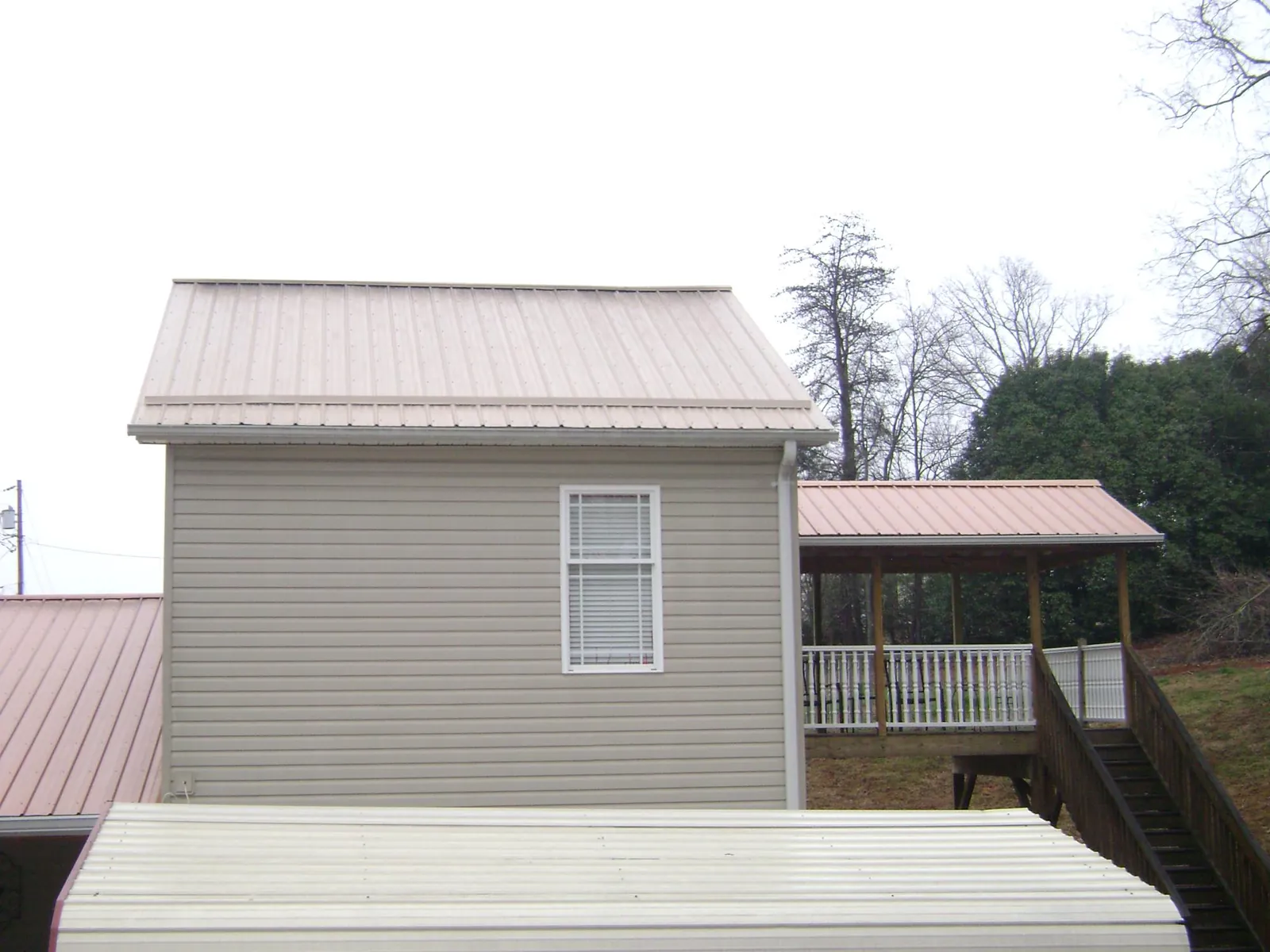 Tan metal roofs on a two story addition and attached porch, from a Roof Replacement job in Eden Prairie