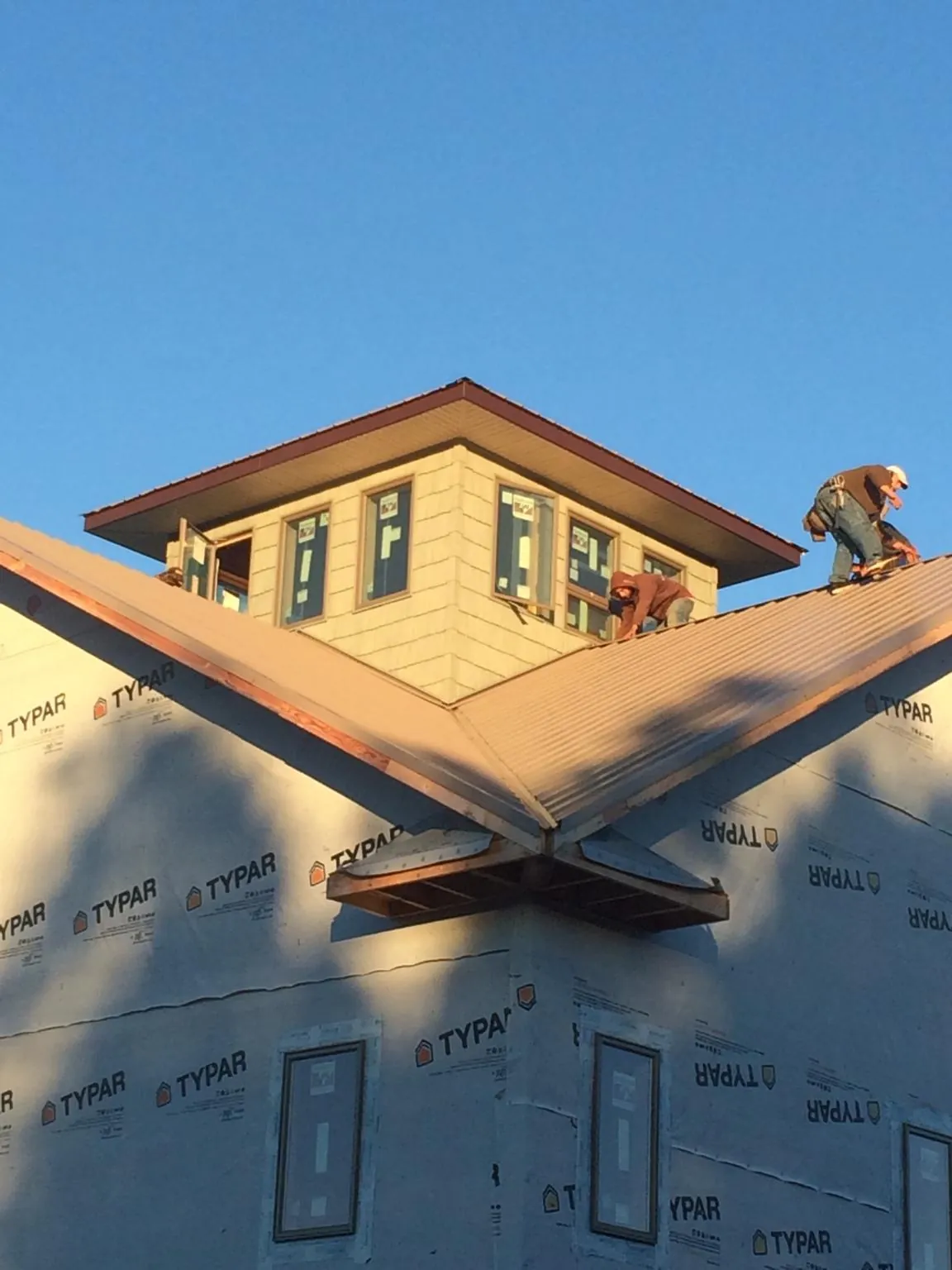 Roofers working around a rooftop cupola on a new metal roof at sunset — Roof Waterproofing in Eden Prairie by Roofing Brothers